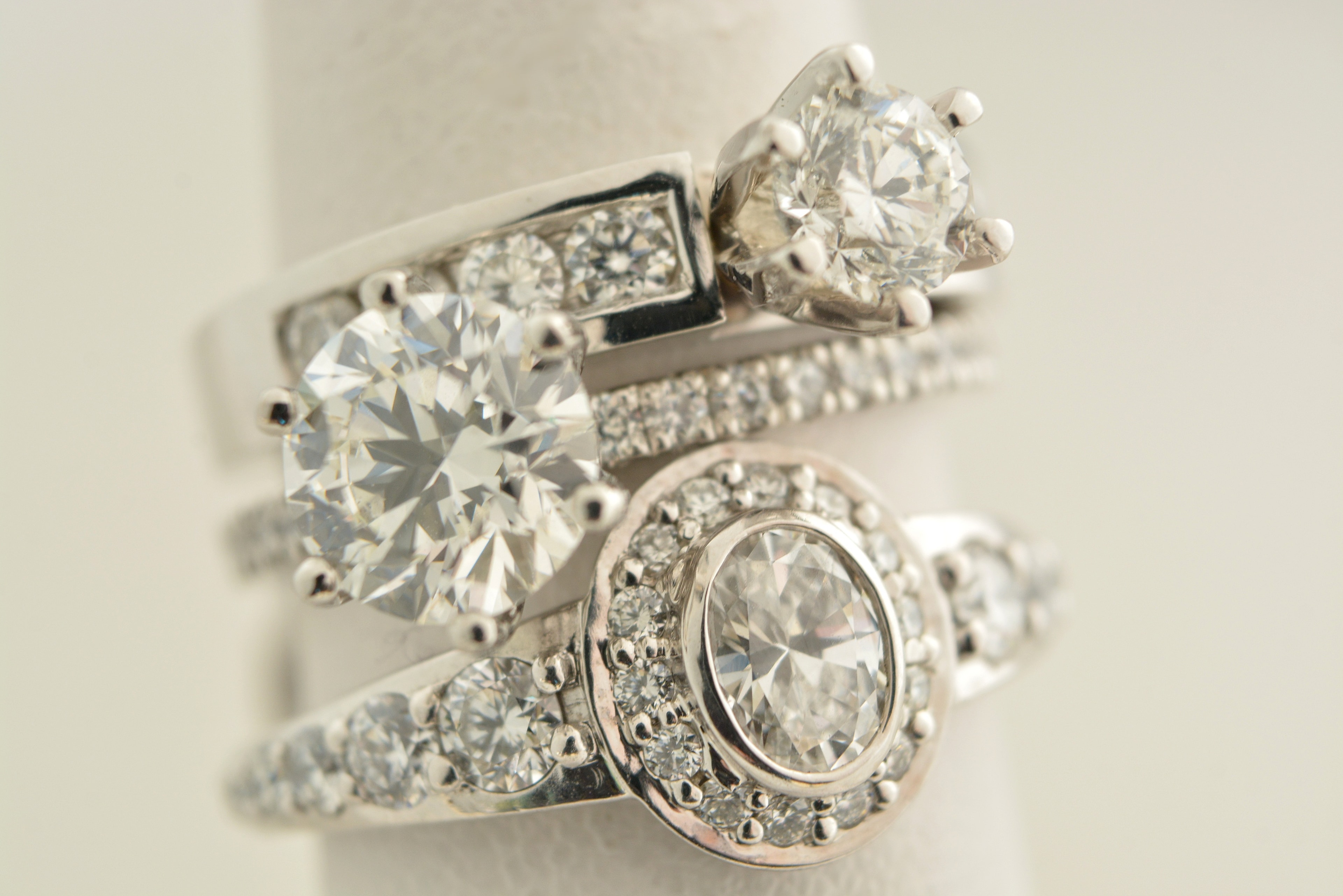 Trois bagues en or blanc serties de diamants taille brillant, présentées sur un porte-bijoux