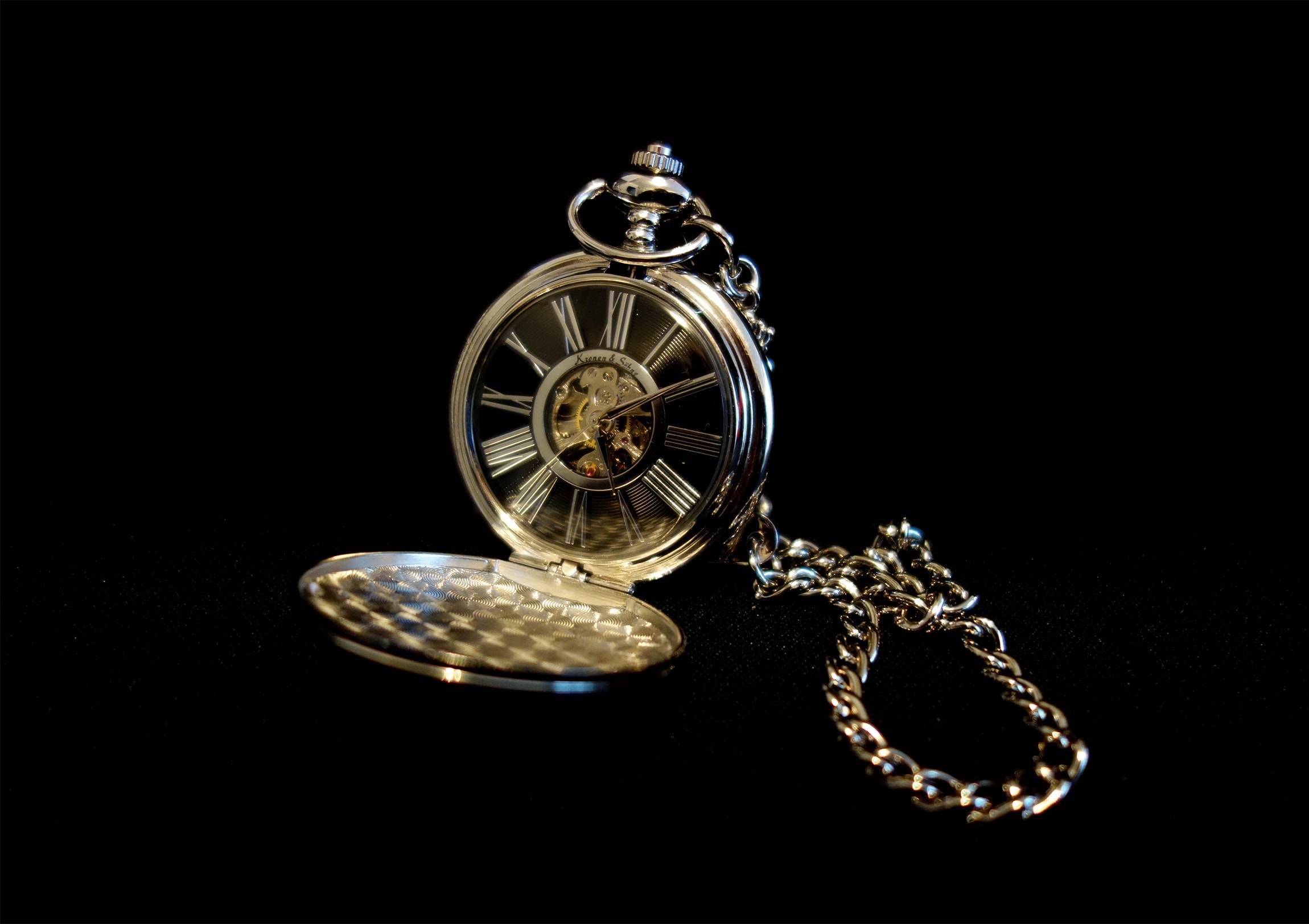 Montre de gousset en or à cadran squelette et chiffres romains, couvercle ouvert et chaîne déployée